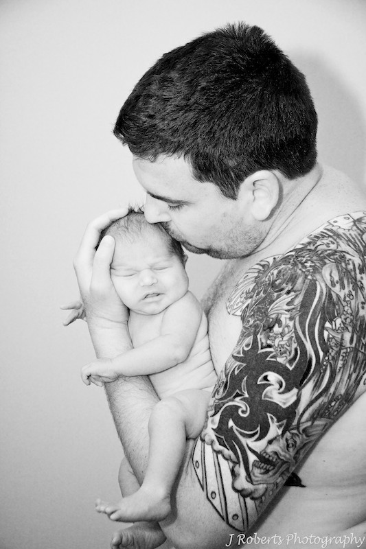 Father kissing newborn baby black and white w tattoos - newborn portrait photography sydney
